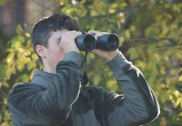 Close up of a young man looking through binoculars