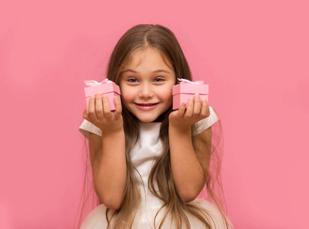 istock little girl on a pink background holding gift boxes 1282795018