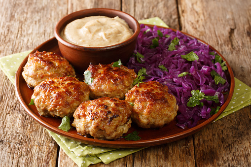 Delicious fried meatballs with hot stewed red cabbage and sauce close-up in a plate. horizontal