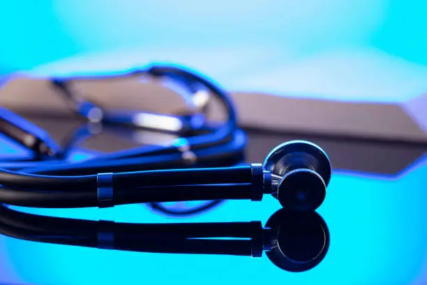 Gavel, legal code and stethoscope on the glass table. Blue light.