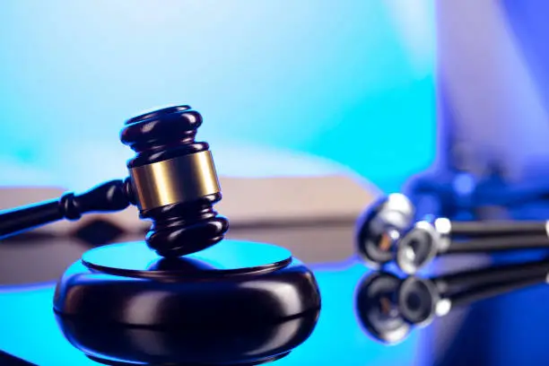 Gavel, legal code and stethoscope on the glass table. Blue light.