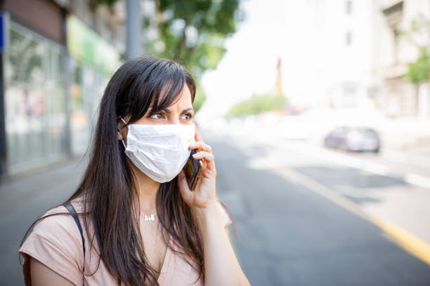 istock Woman with a protective facial mask using mobile phone 1282798623