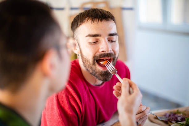 istock Smiling and taking a bite of tomato from his boyfriend's fork 1282800893