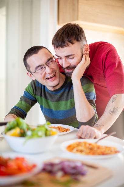 istock Young man sitting and laughing with his boyfriend leaning on him from behind 1282800957