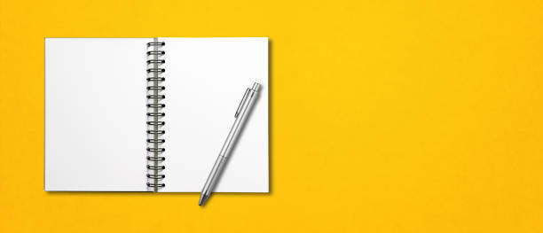 istock Blank open spiral notebook and pen isolated on yellow banner 1282801994