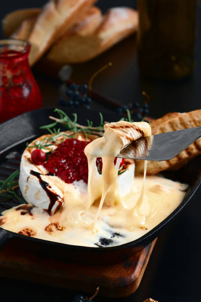 Baked Camembert cheese with cranberry sauce, walnuts and rosemary in a pan.