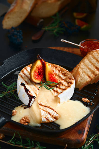 Camembert cheese in a cast-iron pan, oven baked with figs, walnuts and rosemary. Close-up