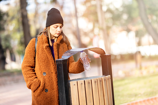 Woman throws plastic trash into the trash can