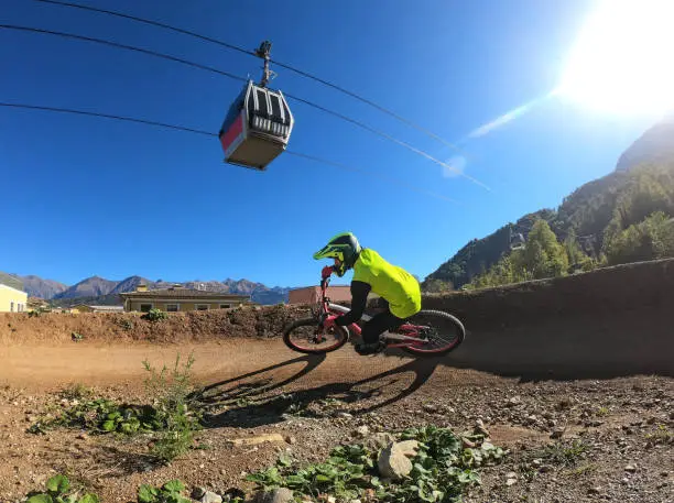 Man riding downhill mountain bike on banked turn of pump track in bikepark