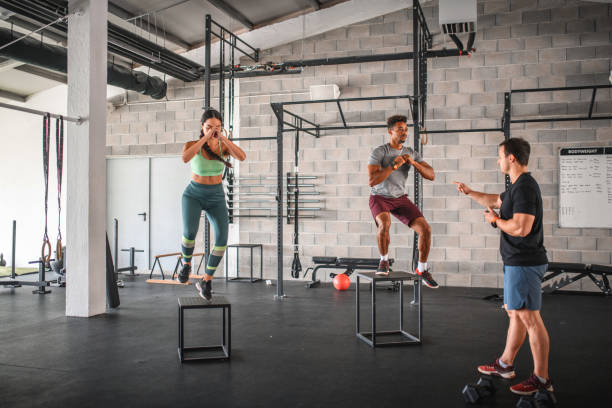 istock Coach Guiding Male and Female Athletes Doing Box Jumps 1282804439