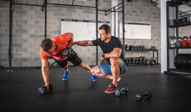 istock Coach Supervising Athlete as He Does Renegade Row Push-Ups 1282804471