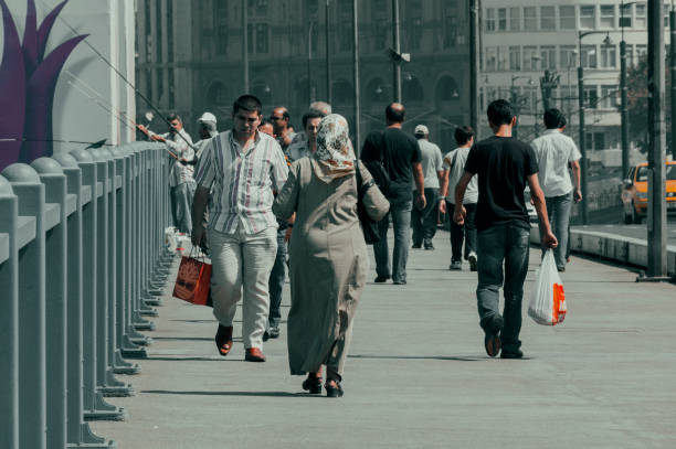 The city of Istanbul, the cultural capital of Turkey, is populous and lively. It has a population of over 15 million, and houses the best examples of religious architecture in the country. Its central part overlooks the Golden Horn, a narrow water channel that creeps into the metropolis. In this image, part of a photographic reportage made in Turkey in 2006, we see a group of people crossing the Galata Bridge suspended over the Golden Horn, and joining the oldest part of the city to the modern part.