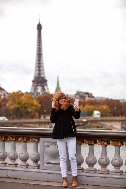 istock Girl using cellphone with Paris city background, Seine river and Eiffel tower. 1282806708
