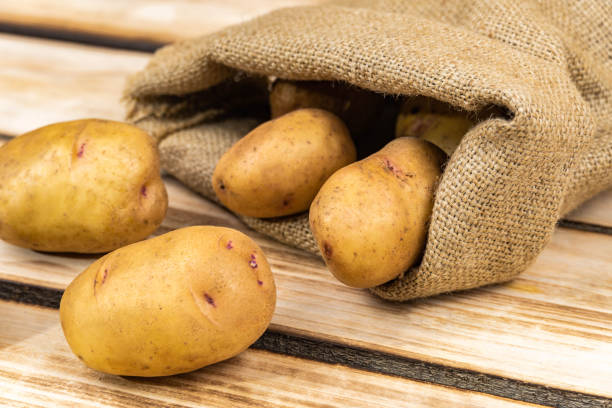 istock Fresh potatoes in an old bag on a wooden background. 1282806953
