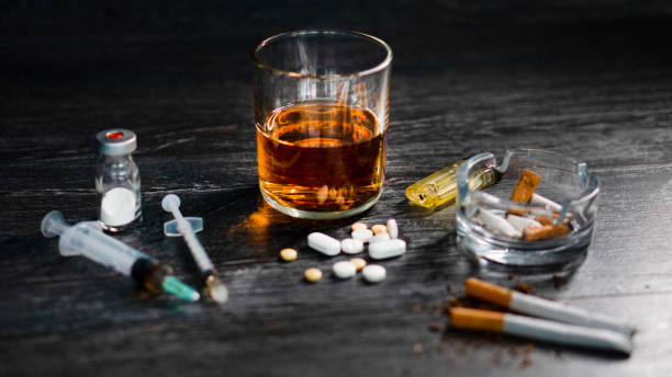 アルコールと薬物やヘロイン、丸薬、ギャンブルとのパーティーで木製のテーブルの上に。 - whisky alcohol bottle hard liquor ストックフォトと画像