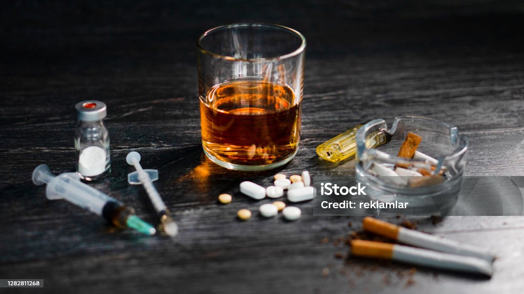 on wood table at party with alcohol and drugs or heroin, pills, gambling. Recreational Drug Stock Photo