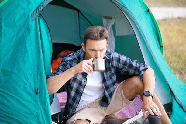 istock Pensive man drinking tea, sitting in tent and looking away 1282812280