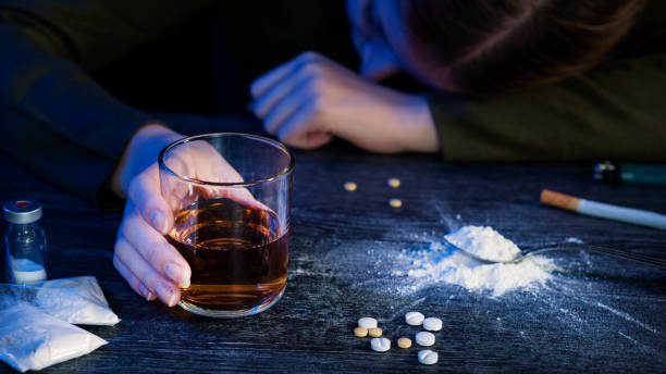 incosciente giovane donna bionda con dipendenza da alcol, whisky e droghe o cocaina, pillole eroina a casa o tavolo da legno - narcotic teenager marijuana drug abuse foto e immagini stock