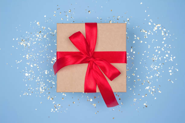 istock Gift box with red bow on festive blue background with golden sparkles around and copyspace for your text. Flat lay style. Christmas, New Year, Valentines Day or birthday celebration concept 1282813629