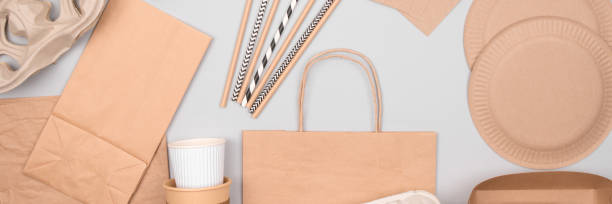 istock Banner with eco-friendly tableware - kraft paper food packaging on light grey background. Street food and fast food paper packaging - cups, plates, straws and paper bags. Flat lay, copyspace 1282813641