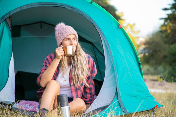 istock Relaxed blonde woman in hat drinking tea, sitting in tent 1282814084