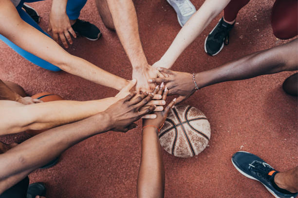 junge sportler halten hände über korbball zusammen - mixed age stock-fotos und bilder