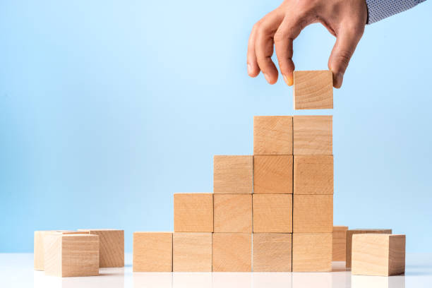 istock Businessman hand Arranging Wood Block Stacking as Step Stair on blue background 1282820187