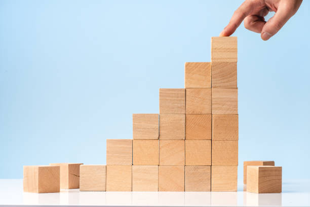 istock Businessman hand Arranging Wood Block Stacking as Step Stair on blue background 1282820244