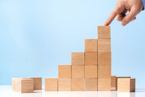 istock Businessman hand Arranging Wood Block Stacking as Step Stair on blue background 1282820498