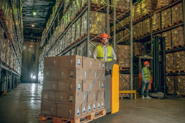istock Two workers in helmets and vests working in the warehouse 1282823524