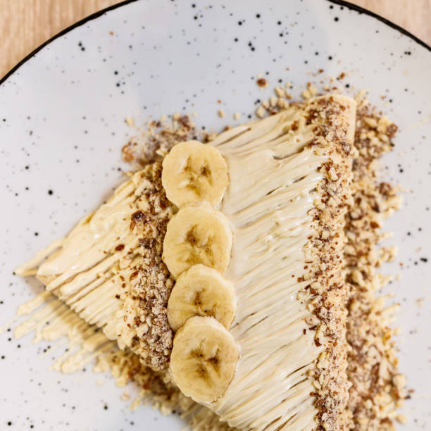 istock Delicious crepes with bananas, white chocolate spread, and crushed nuts 1282824180