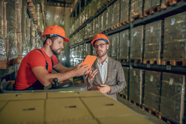 istock Warehouse worker showing data from internet to the warehouse manager 1282824369