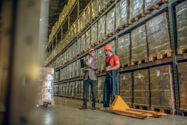 istock Two men in orange helmets talking in the warehouse 1282824416