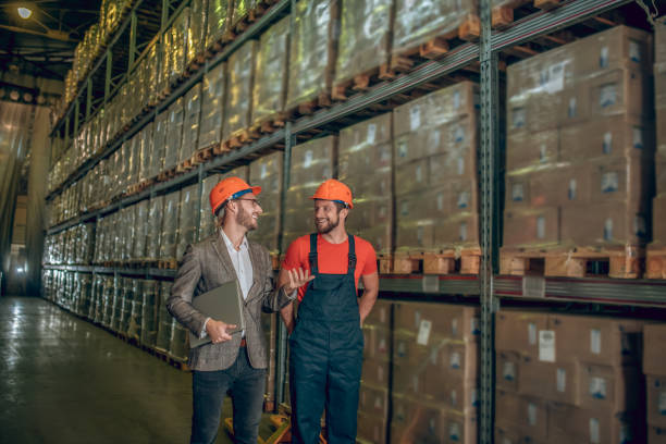 istock Manager in orange helmet talking to the worker while inspecting the warehouse 1282824440
