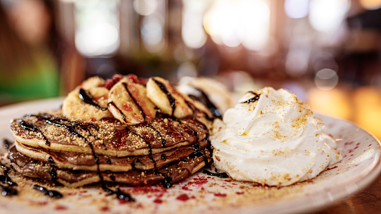 Delicious pancakes topped with chocolate sauce, banana slices and berries