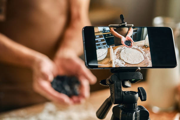 Male blogger filming video content about cooking pie Chef holding handful of blueberries while making pie at home and recording vlog. Live streaming concept live broadcast photos stock pictures, royalty-free photos & images