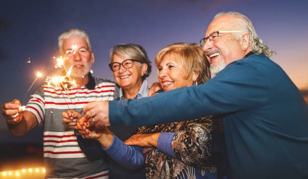 feliz familia de la tercera edad celebrando con fuegos artificiales de chispas en la fiesta en casa - el estilo de vida de las personas mayores y el concepto de vacaciones - retirement grandfather senior adult child fotografías e imágenes de stock