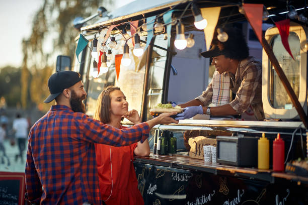 coppia soddisfatta prendendo panini ordinati da un impiegato educato e amichevole - food truck foto e immagini stock