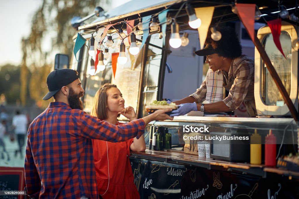 satisfied couple taking ordered sandwiches from an polite and friendly employee satisfied couple taking ordered sandwiches from an polite and friendly and polite employee Food Truck Stock Photo