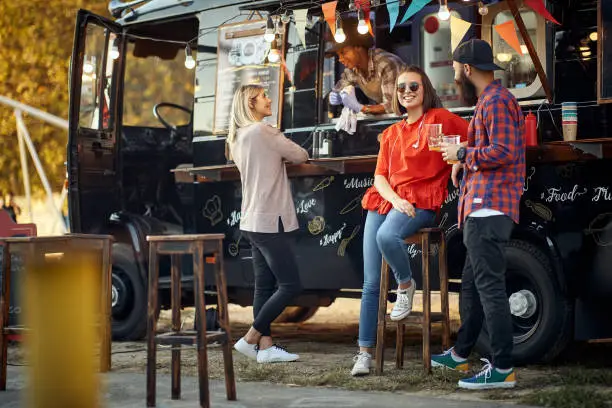 smiling customers of fast food truck having conversation between themselves and with employee