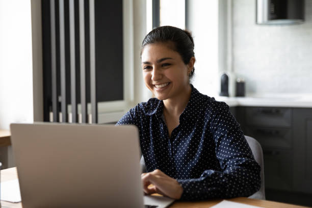 istock Smiling Indian female work on laptop in office 1282833208