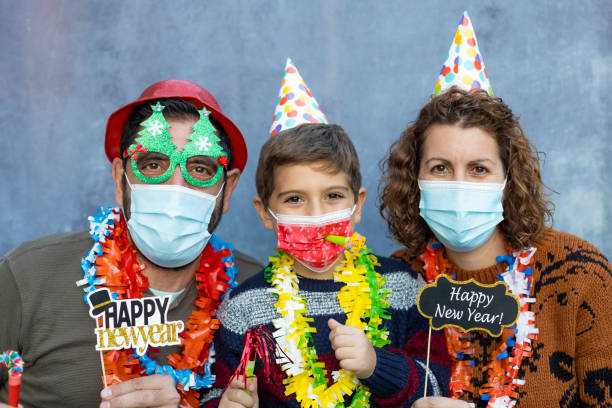 glückliche familie mit gesichtsmasken feiern silvester - 6 7 years fotos stock-fotos und bilder
