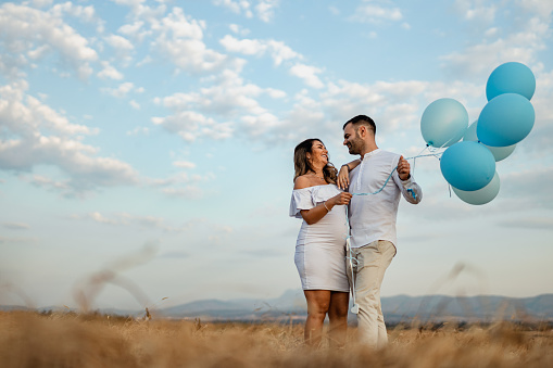 Asian couple holding colorful balloons on the beach in sunny day.