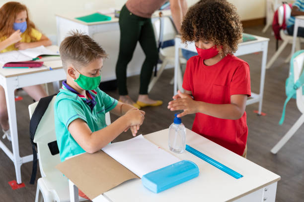 istock Two boys wearing face masks sanitizing their hands in class at school 1282835066