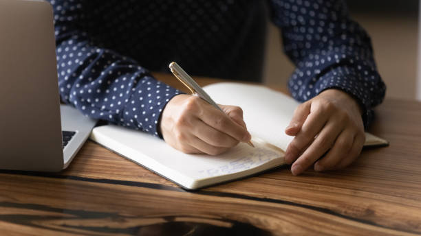 istock Crop of woman write note in paper notebook 1282835160