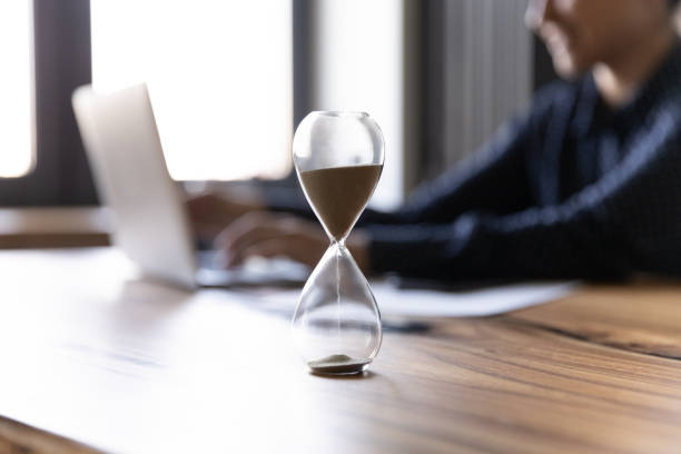 istock Crop of hourglass on table with employee working on background 1282835177