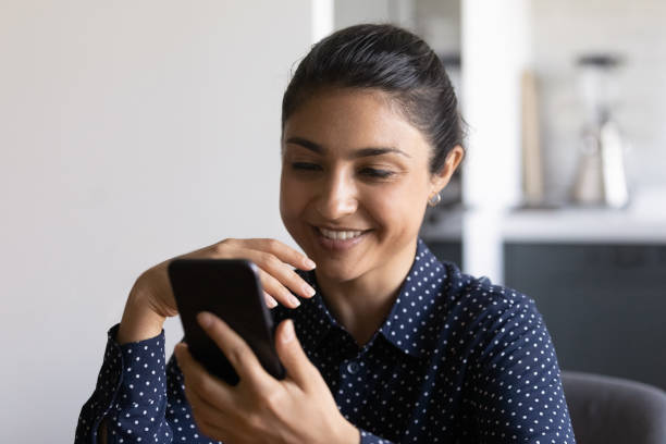 istock Smiling Indian woman using modern cellphone gadget 1282835181
