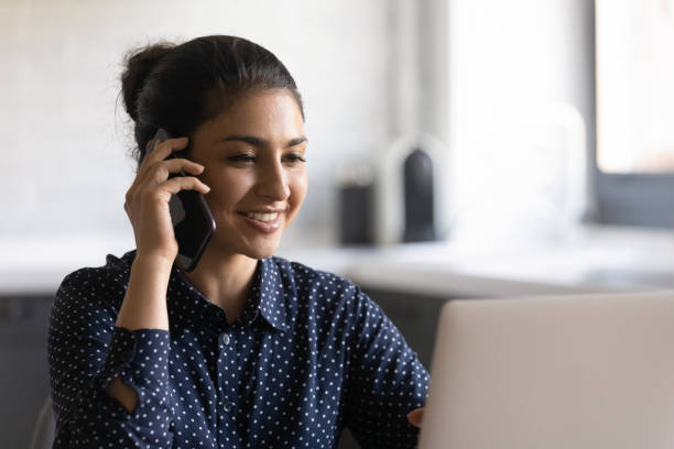 istock Smiling Indian woman work on laptop talking on cell 1282835189
