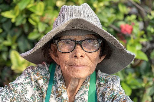 Koh Phangan, Thailand - may 11, 2019 : Portrait of an old woman with glasses and a hat on a street market in island Koh Phangan, Thailand , close up
