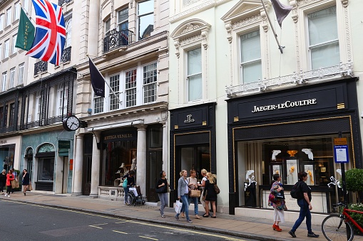 People walk by Jaeger-LeCoultre, Bottega Veneta and Colnaghi shops at Old Bond Street in London. Bond Street is a major shopping street in the West End of London.